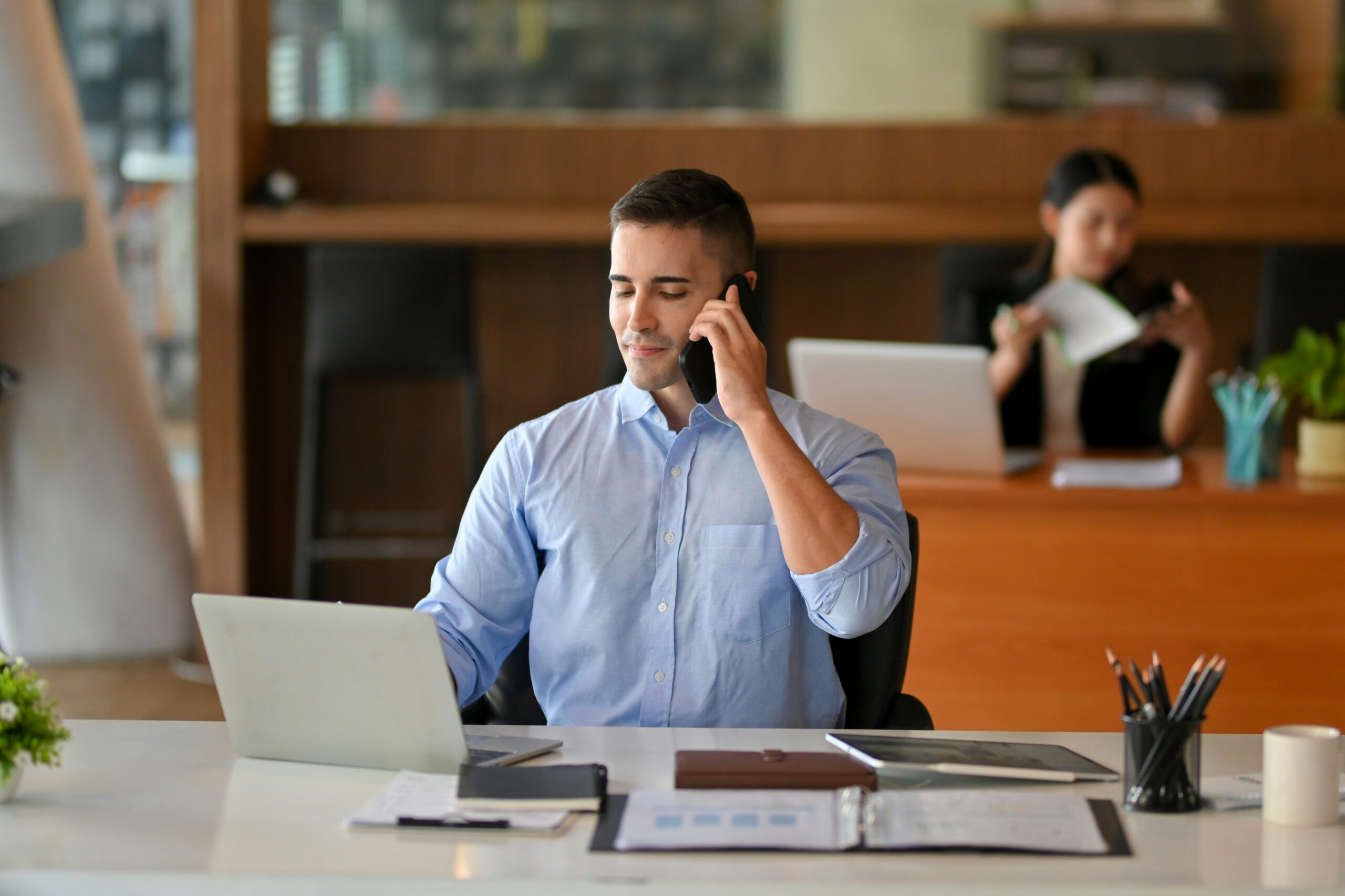 Young business man sitting at his desk while smiling at his computer