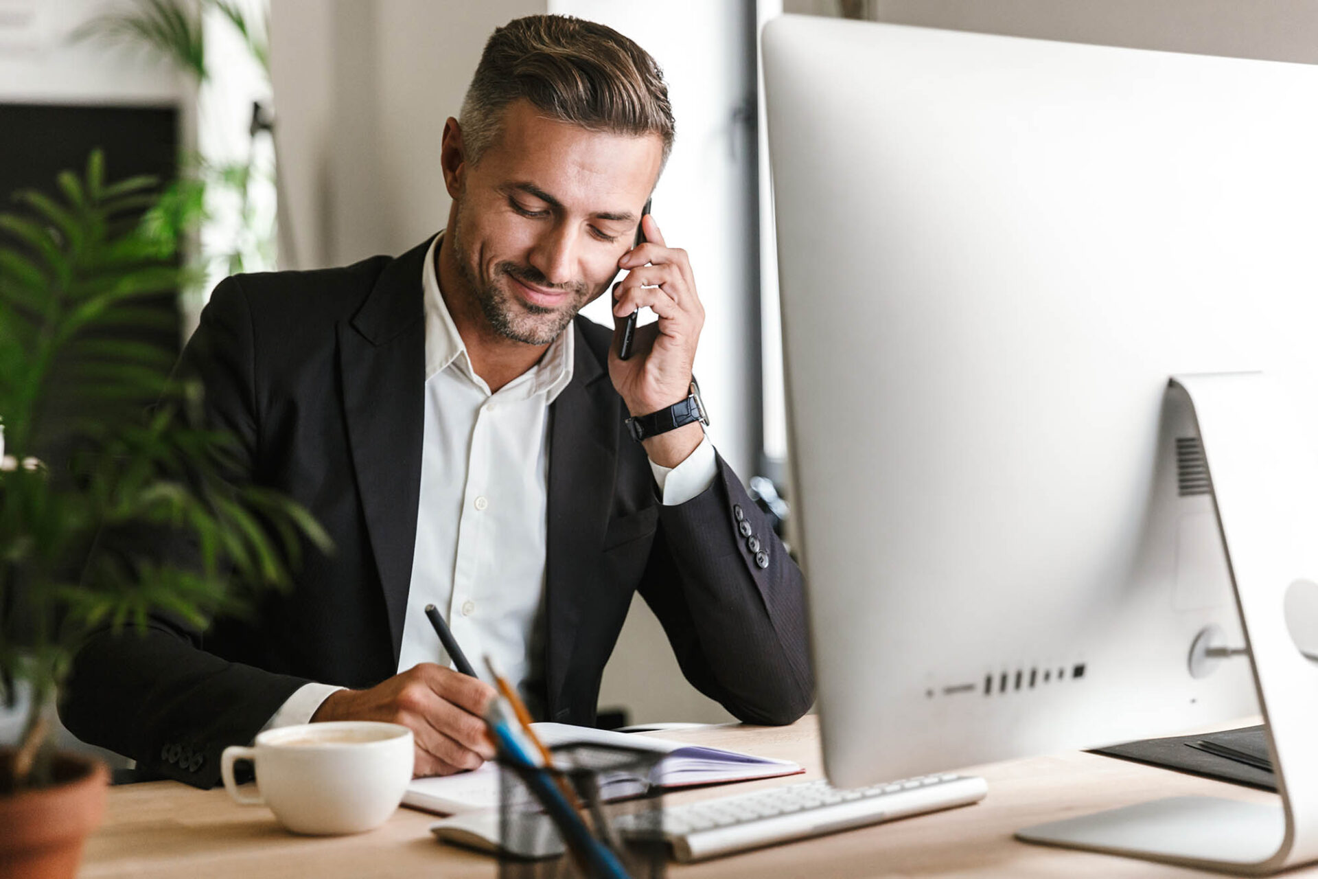 Business executive on phone call while reviewing audit and compliance notes at office desk