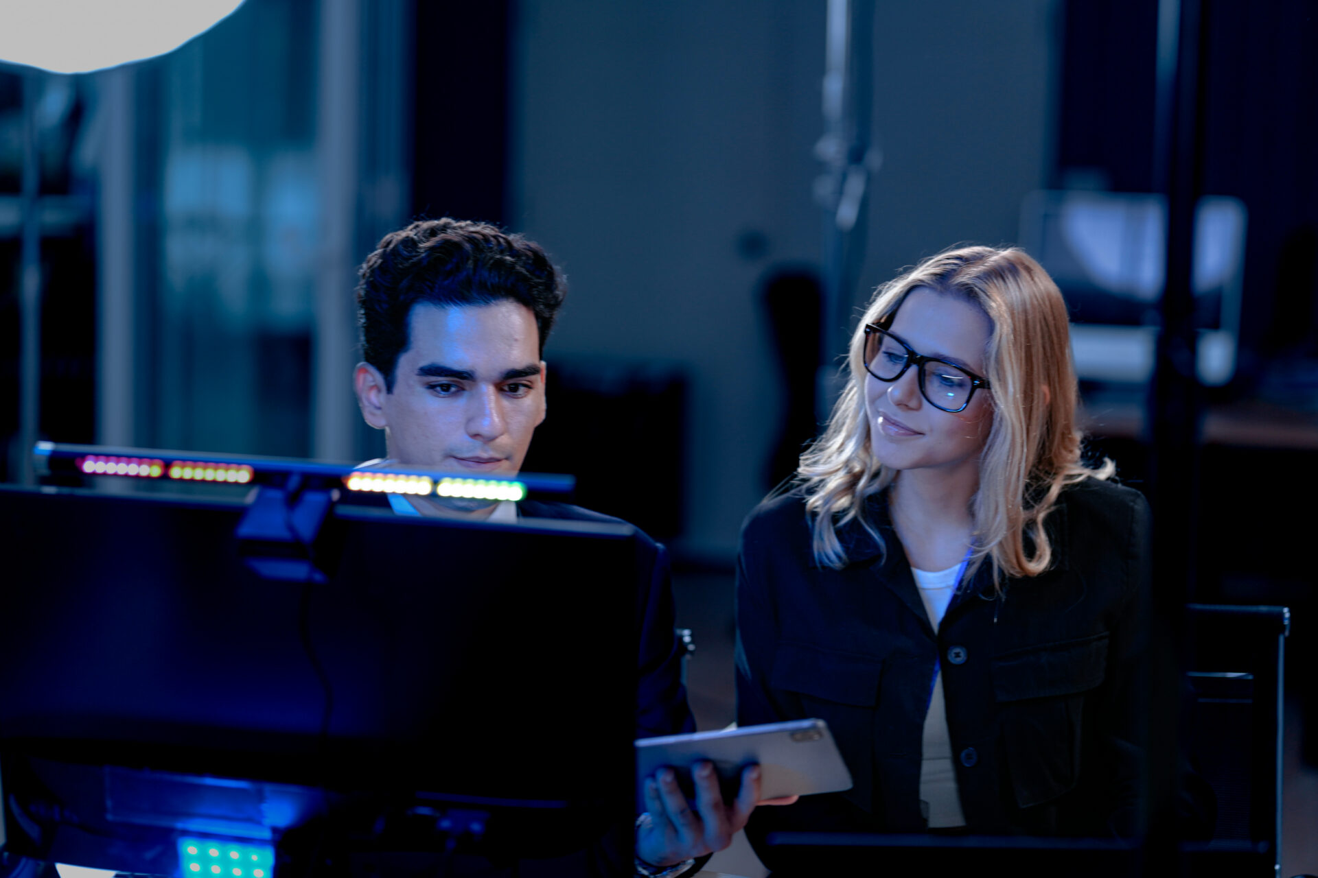 Future AI validation meeting. Human oversight lead points out discrepancies comparing AI generated report data against real time system performance displayed on control screen.